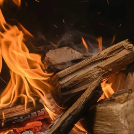 Firewood burning in a fireplace with flames and embers.